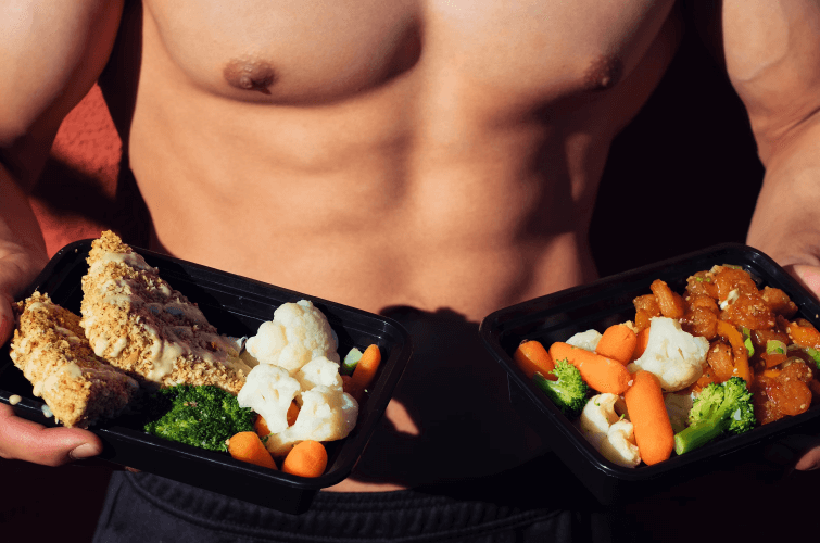 Hombre fitness sosteniendo alimentos saludables como brócoli, pollo y zanahoria